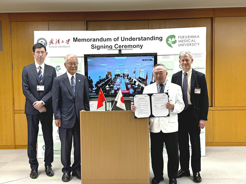 左から 企画財務課 川崎新太朗課長、国際交流センター山下俊一センター長 中央の画面武漢大学、竹之下誠一理事長兼学長、ノレット・ケネス教授