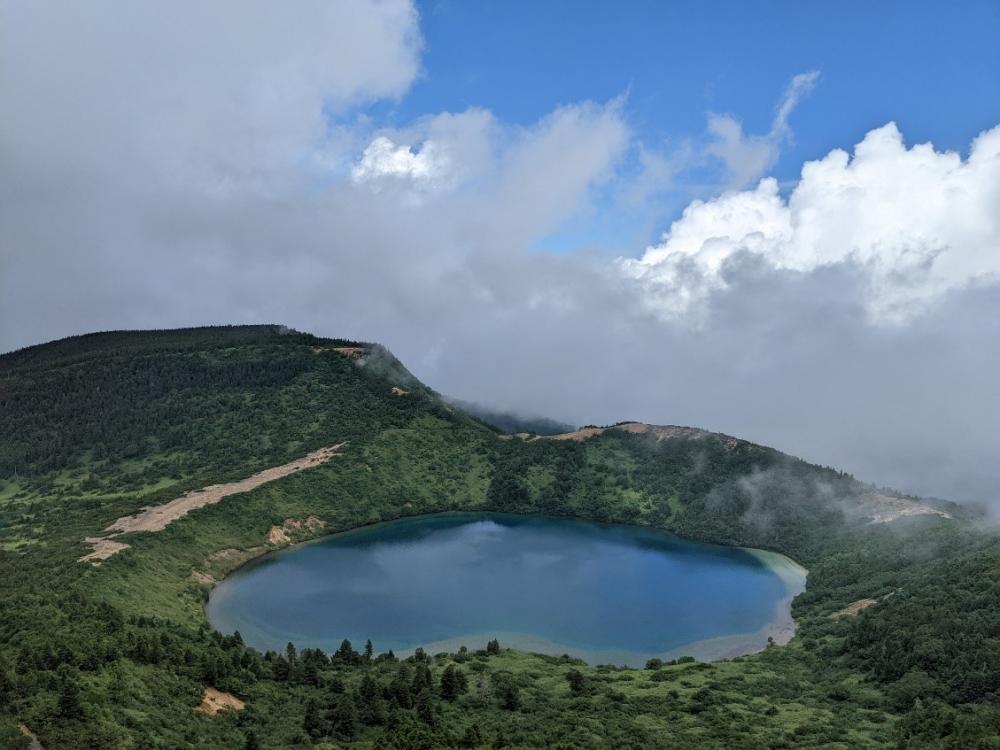 一切経山の頂上から見た五色沼の美しい風景、青空と雲に囲まれたカルデラ湖。